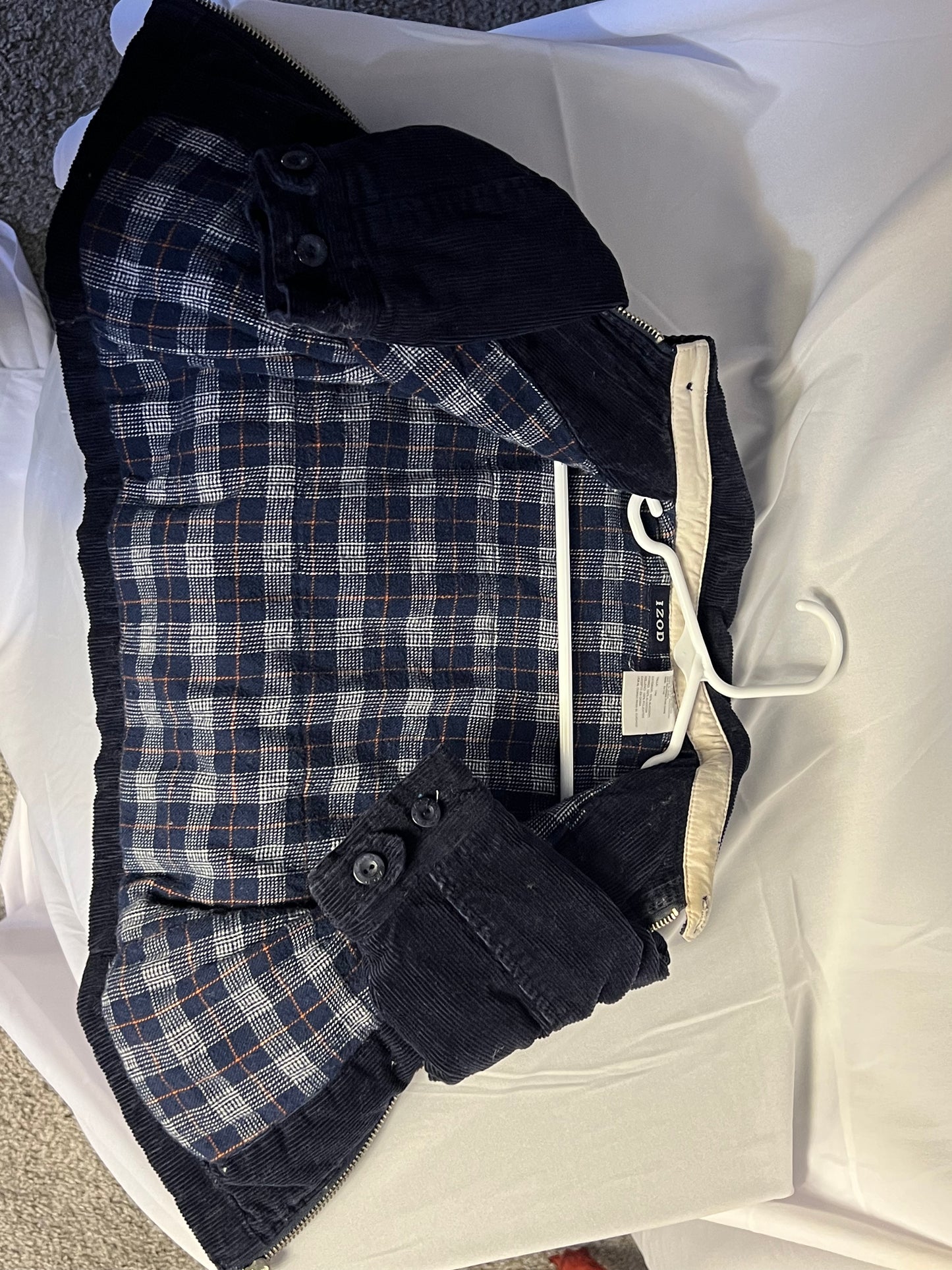 Folded navy and white plaid jacket with tags on a white surface